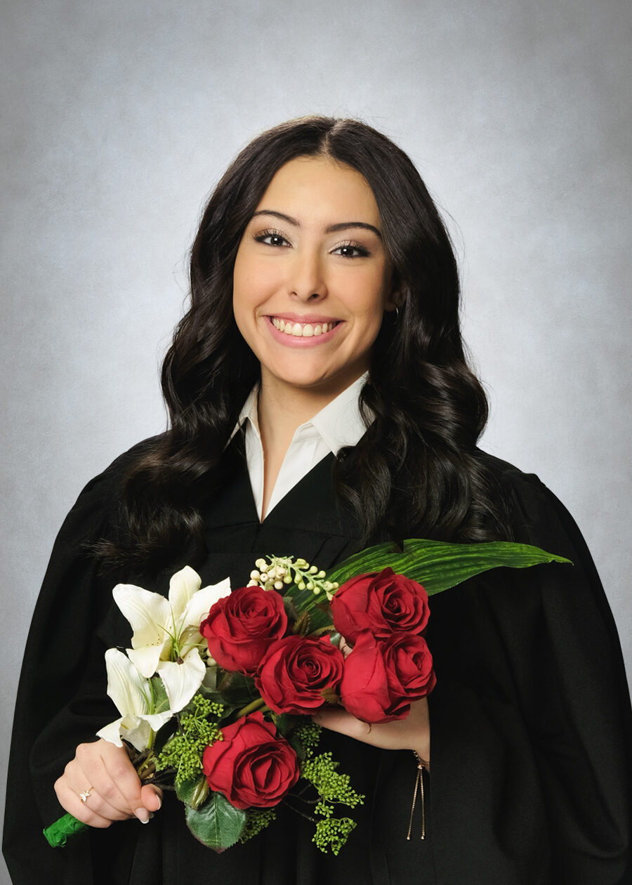 GradPase_Flowers A high school graduation portrait of a girl wearing a graduation gown and holding flowers against a traditional grey background.